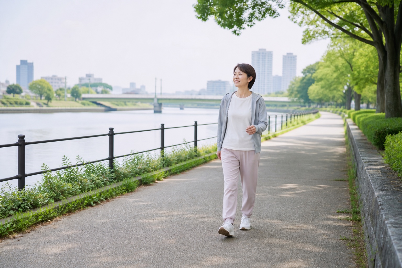 腰と脚の様子を見ながら平坦な川沿いを歩く女性