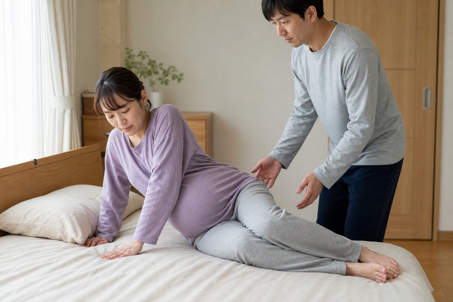 身体をひねらず横向きから腕で起き上がる妊娠中の女性と見守る家族