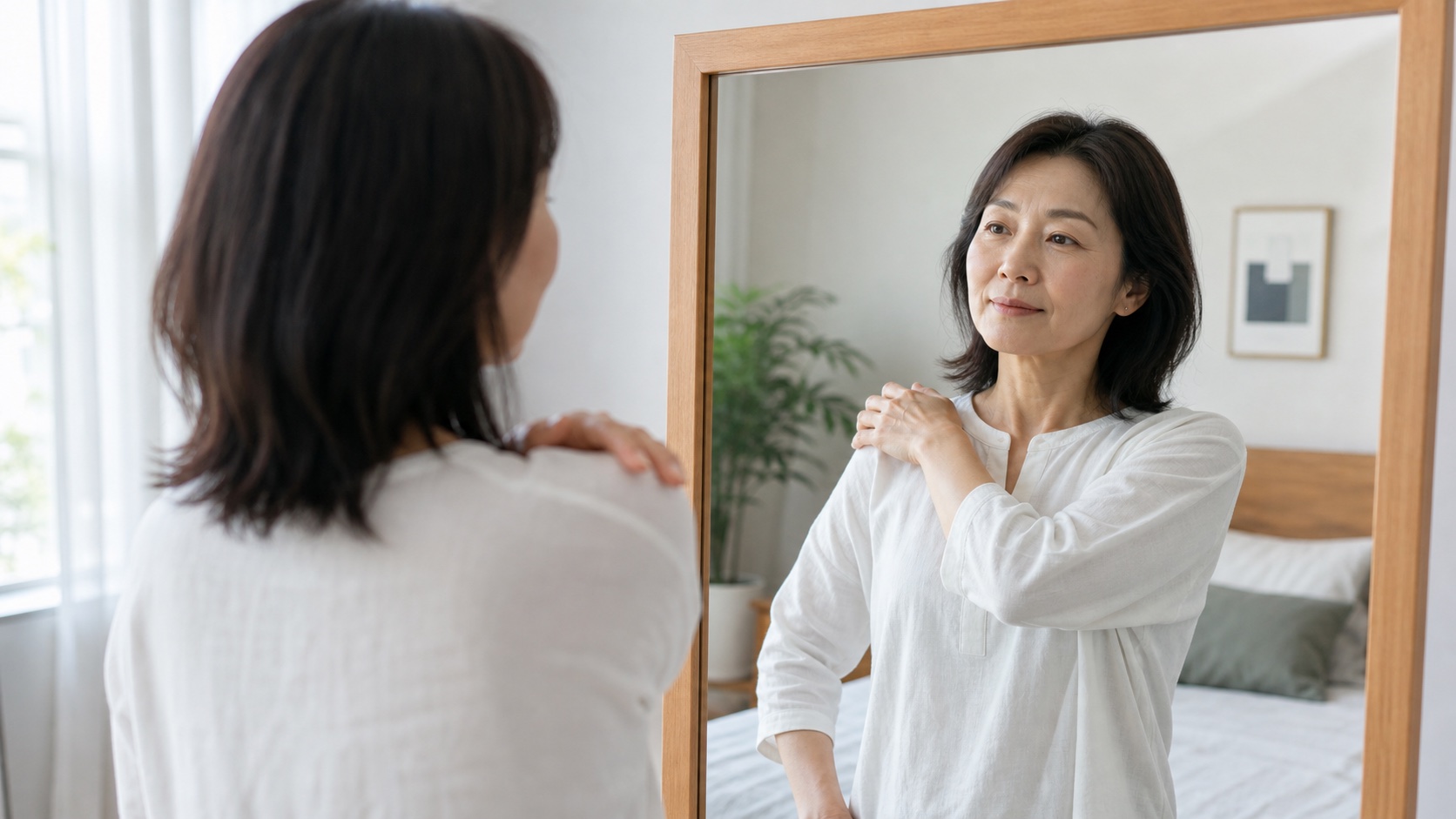 鏡の前で肩の動かしやすさを確認する女性
