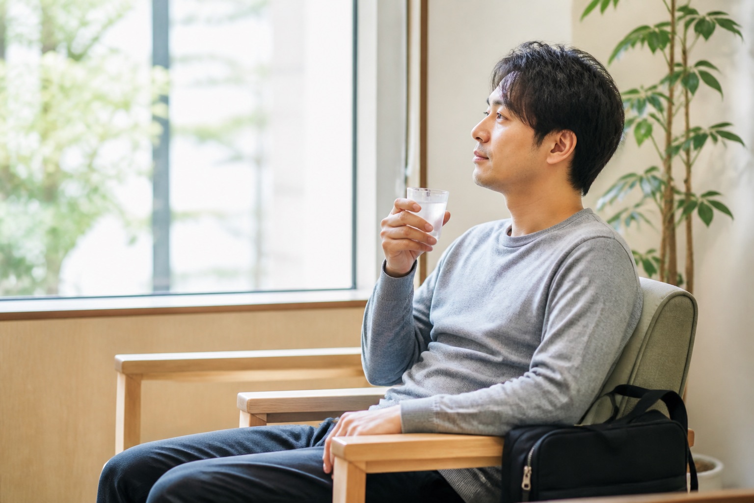 MRI検査後に病院の窓辺で少量の水を飲み休む男性