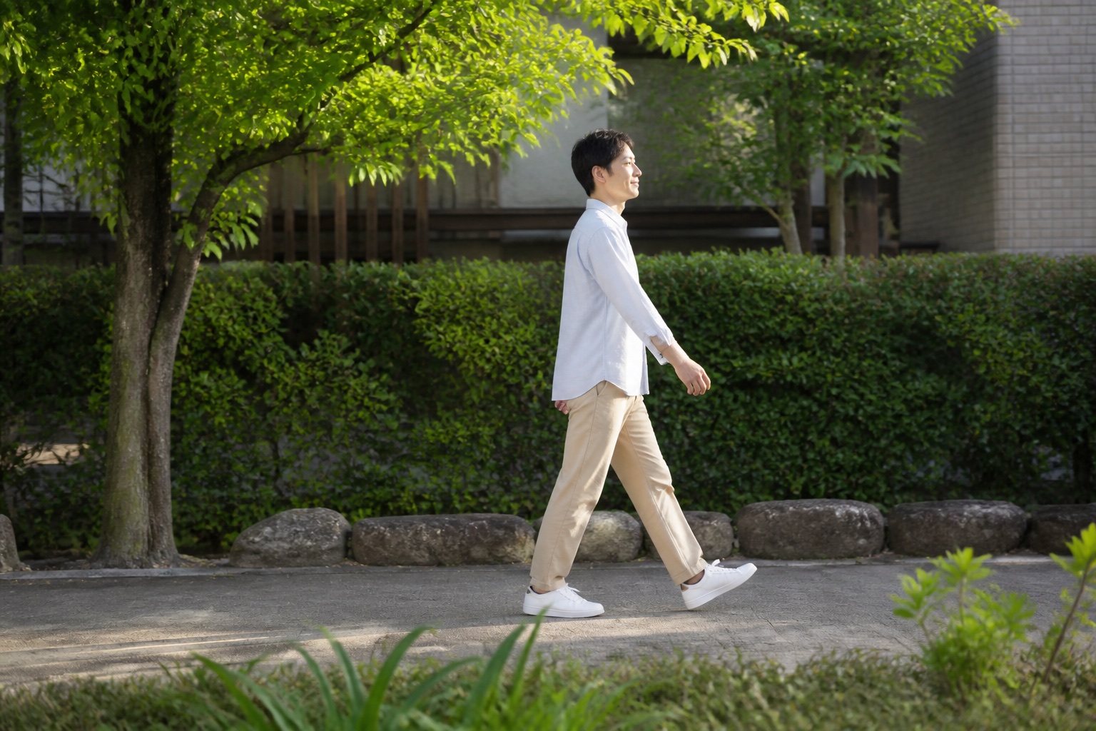 食後に無理のない速度で緑道を歩く男性