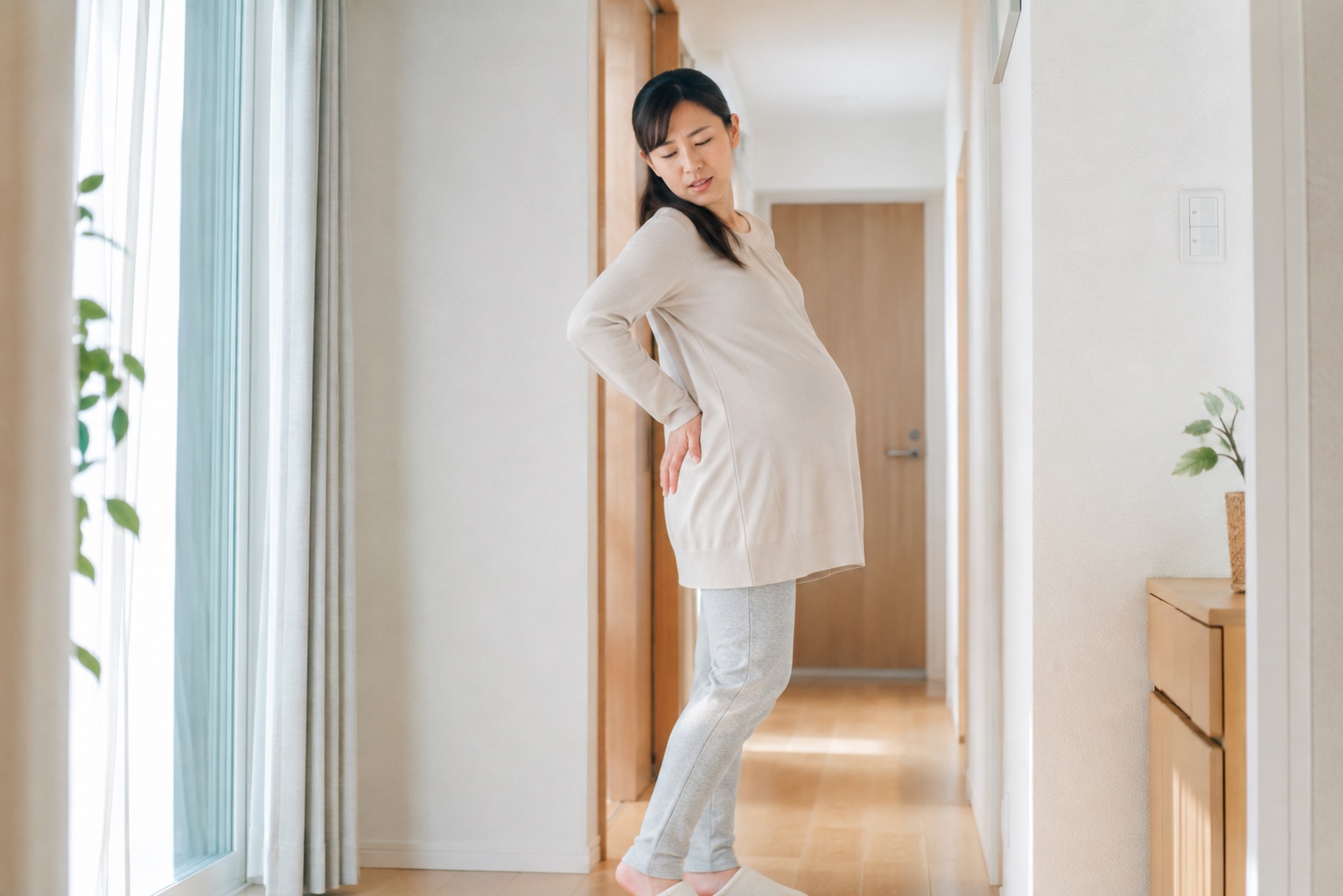 妊娠中に歩くと片側のおしり周辺が痛み室内で立ち止まる女性