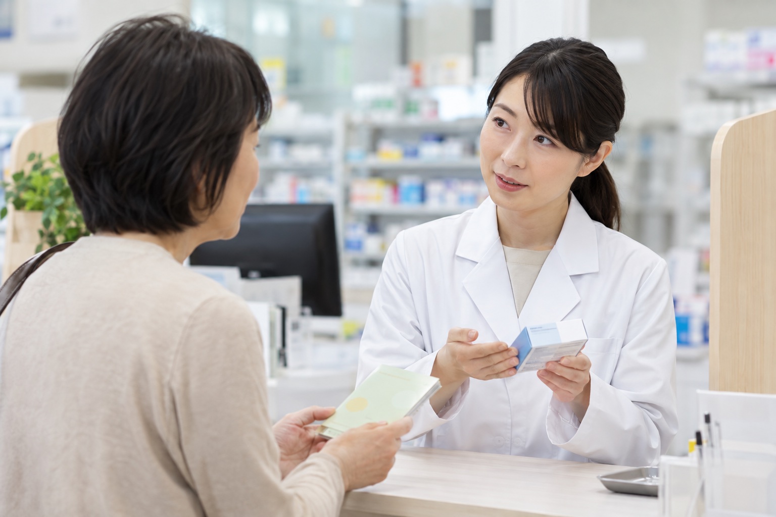お薬手帳を見せながら市販薬について薬剤師へ相談する女性