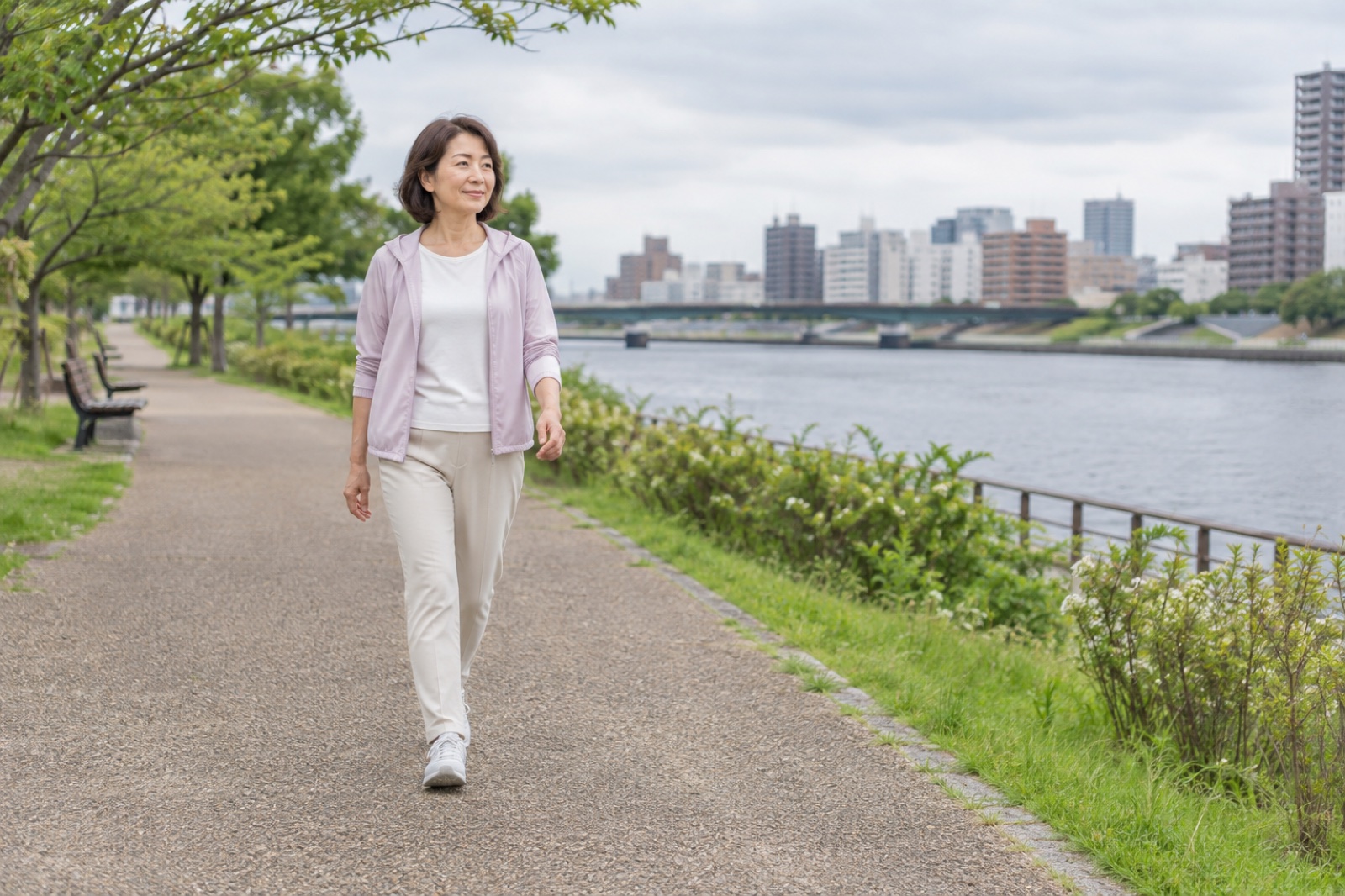 平坦な川沿いを無理のない速さで歩く50代女性